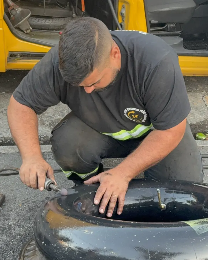 Gui fazendo remendo em câmara de ar ao lado do carro da borracharia